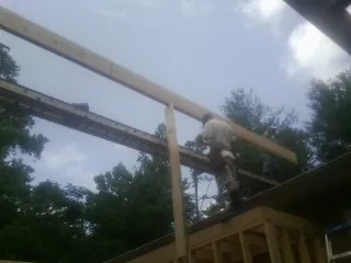 Carpenter setting a ridge beam over a new addition frame — Ice Dam Removal by Roofing Brothers in Grubville