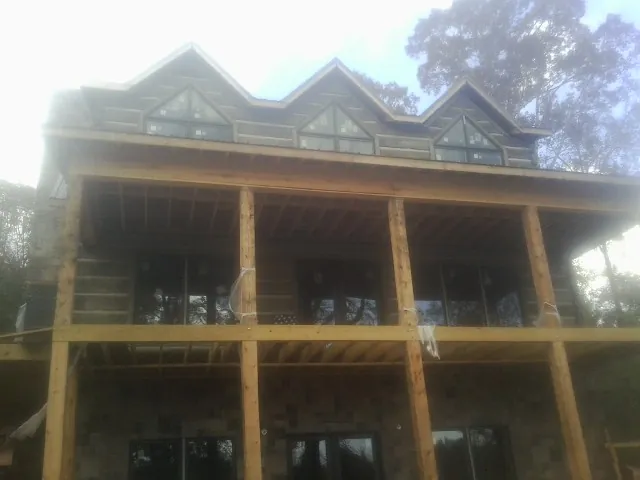 Dormers and porch framing on a large log home under construction — Roof Coating work by our crew in Grubville