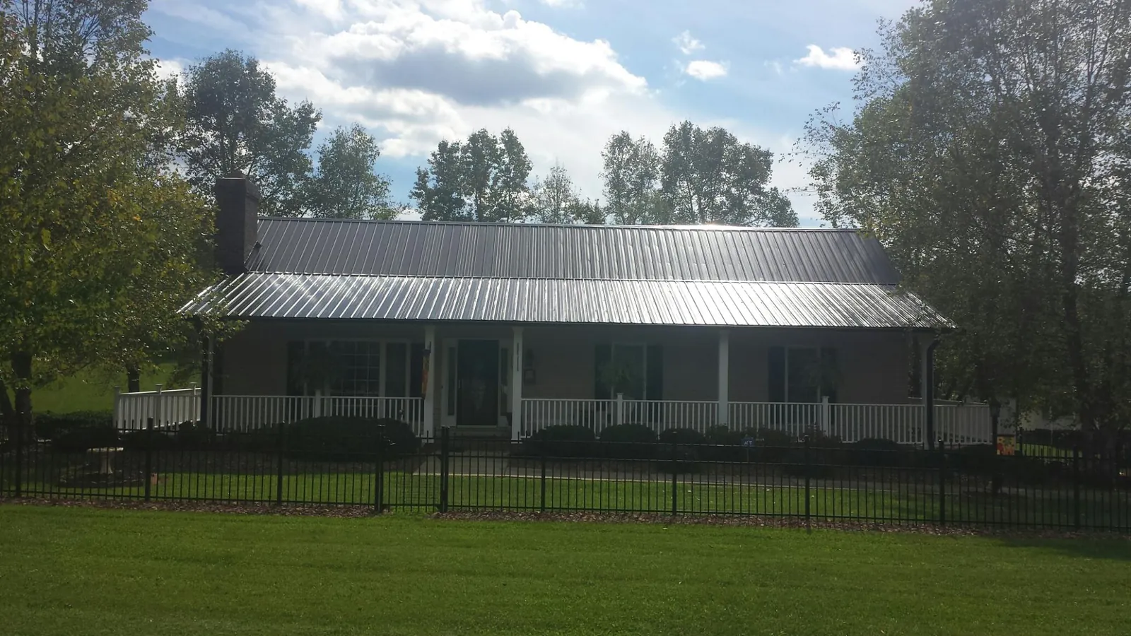 Gray metal roof on a brick ranch with a full width front porch — Gutter Guard Installation work by our crew in Grubville