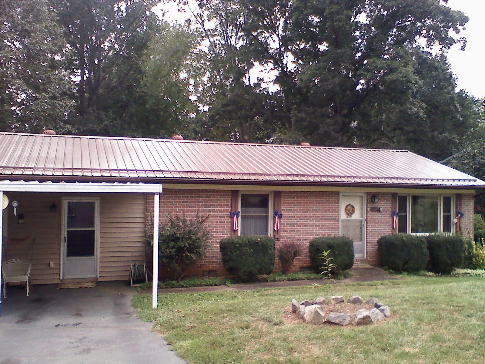 Bronze metal roof and carport on a brick ranch home — Roof Repair work by our crew in Grubville