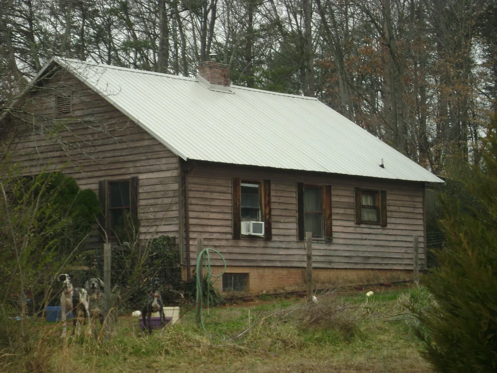 White metal roof on an old wood sided farmhouse, from a Asphalt Shingle Roof Repair job in Grubville