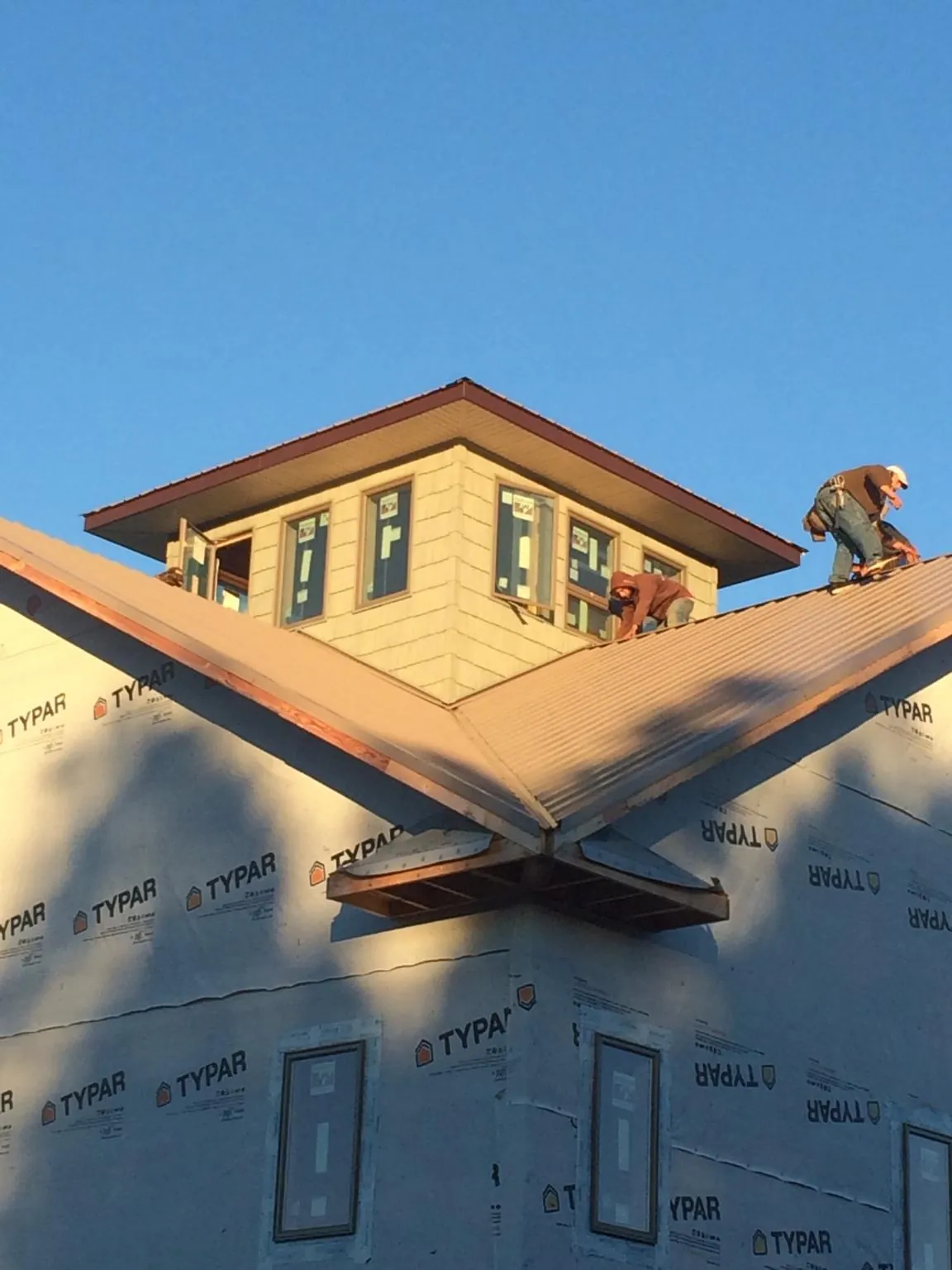 Roofers working around a rooftop cupola on a new metal roof at sunset — Roof Waterproofing in Grubville by Roofing Brothers